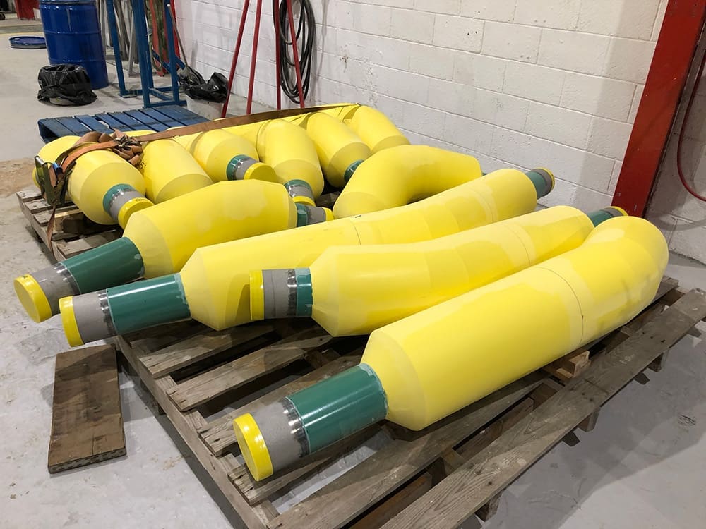 Yellow polyurethane-insulated subsea pipe spools stacked on pallet at LJF Custom Coatings facility